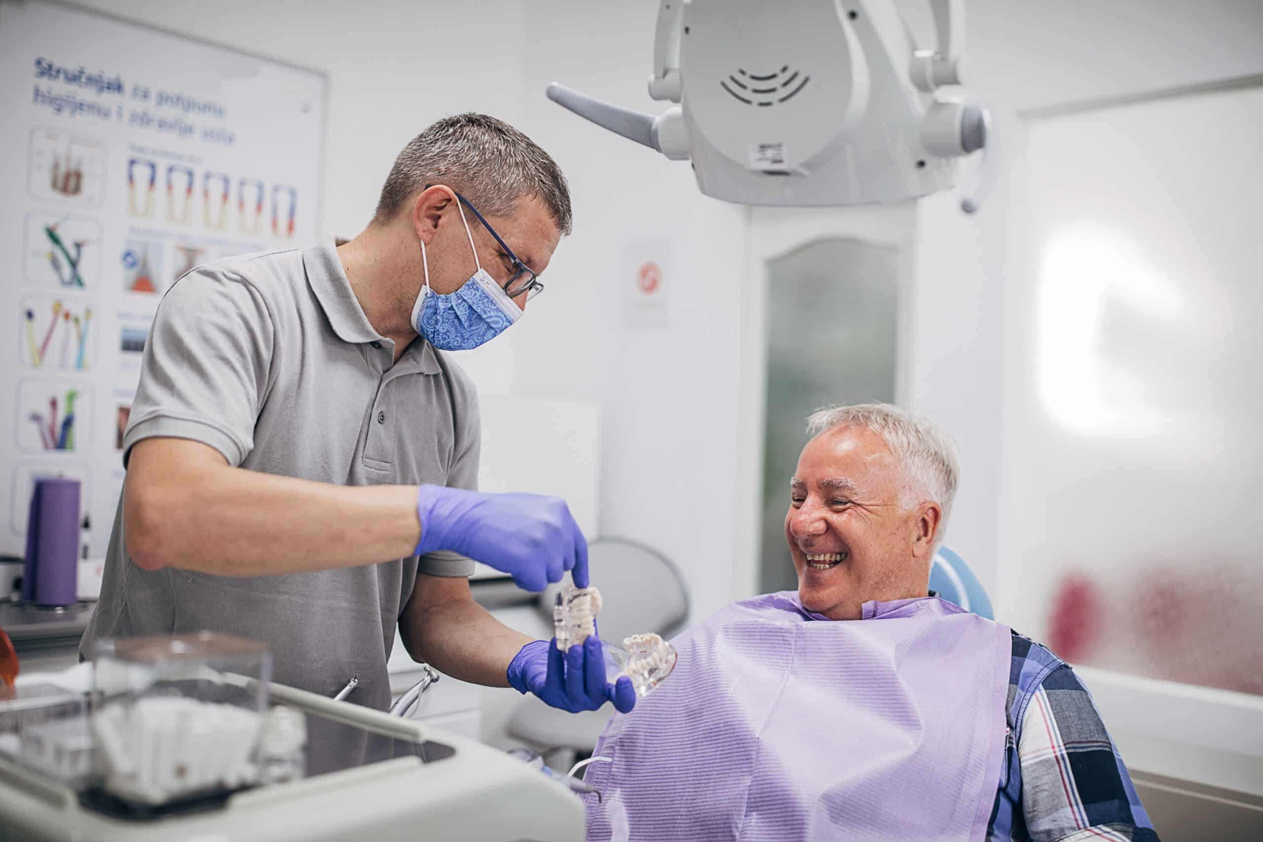 A male dentist explaining to a male patient how dentures are made