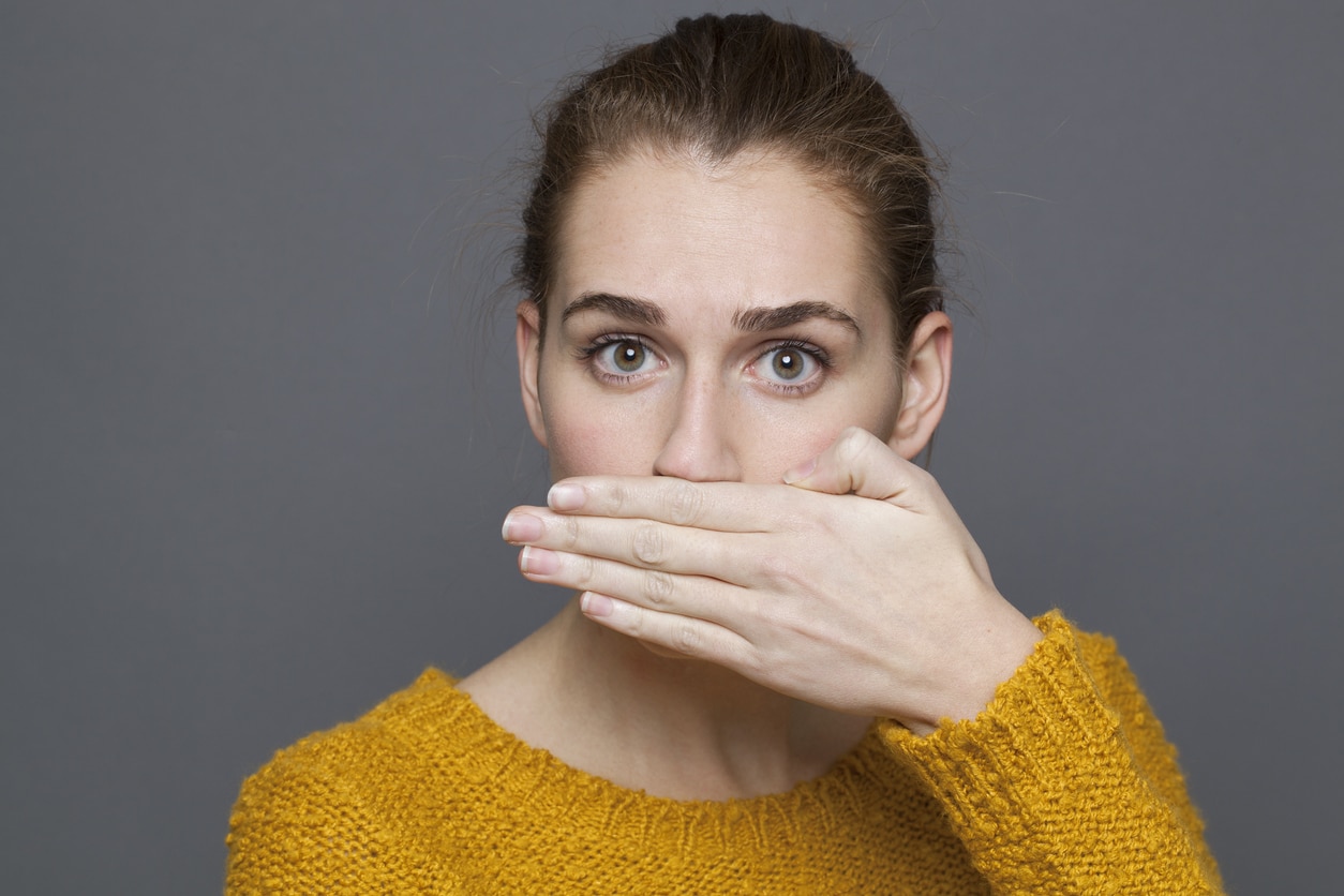 Portrait of a surprised young woman covering her mouth.