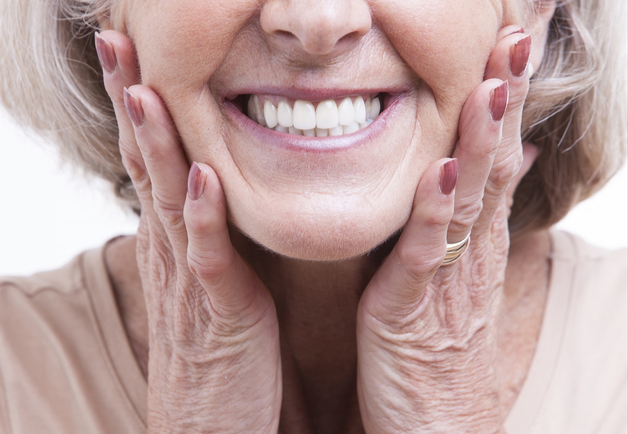 Older woman smelting with her hands on the side of her face.