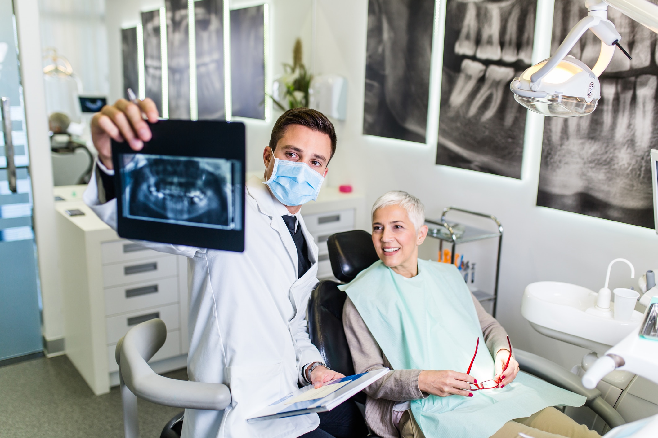 A dentist reviewing a jaw X-ray with a patient to assess bone density for dental implants.
