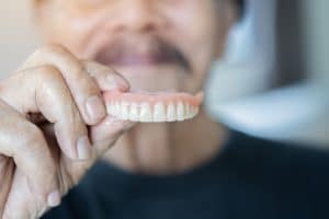 A close-up of a loose denture being held by a patient.