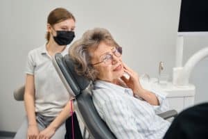 A patient in a dental chair at Shelby Dental Center discussing denture discomfort with their dentist during an appointment.