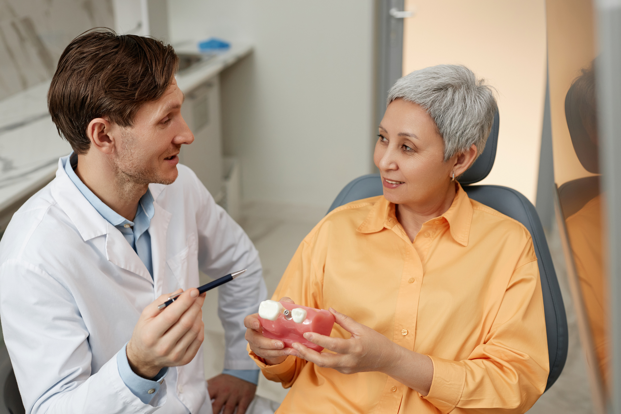 A dentist at Shelby Dental Center in Calera, Alabama discussing partial and full denture options with a patient during a consultation.